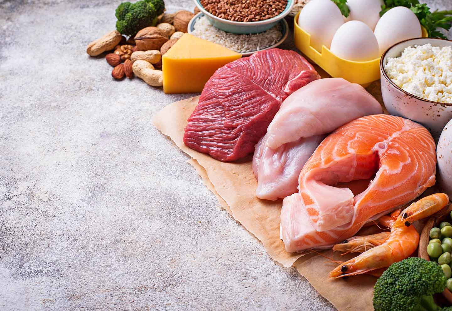 Verschiedene rohe Zutaten wie Fleisch und Fisch liegen ansprechend arragniert auf einer Fläche